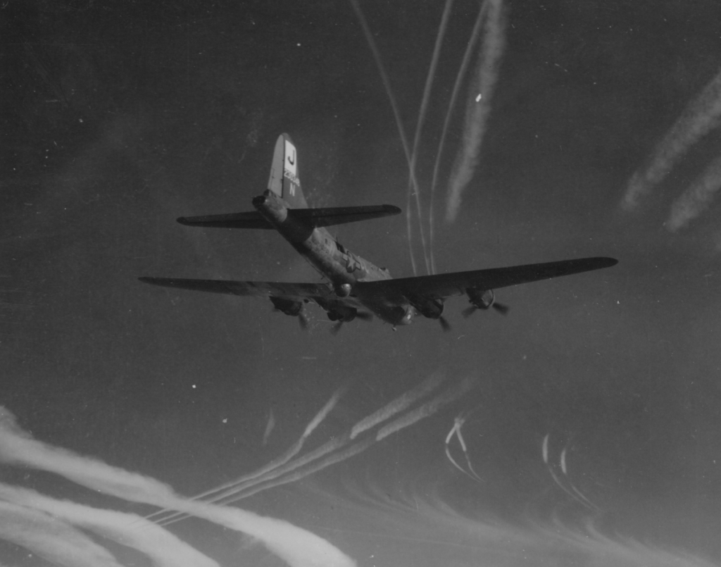 a b-17 heavy bomber plane flying with contrails from other planes around it, black and white photograph